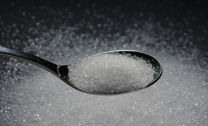 a spoon filled with sugar on top of a table