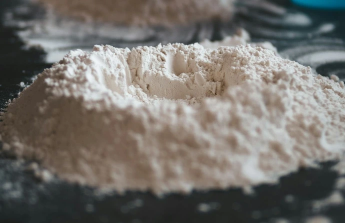 person holding white powder on brown wooden table